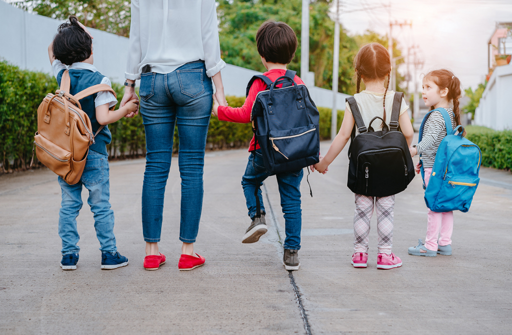 Children wearing back packs accompanied by an adult
