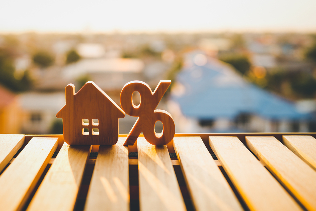 Percentage and house sign symbol icon wooden on wood table. Concepts of home interest, real estate, rates, investing in inflation.