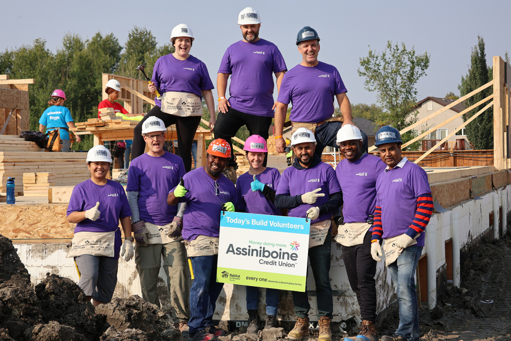 The ACU team pictured smiling and posing in front of a Habitat for Humanity construction site