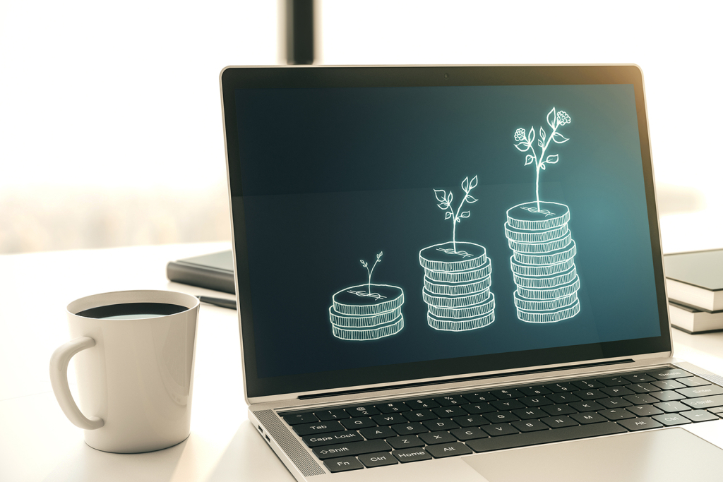 Open laptop displaying increasingly tall stacks of money next to a coffee cup