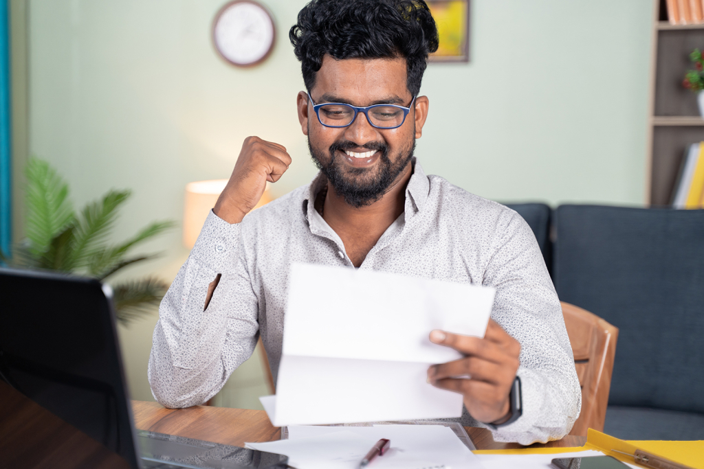 Student pumps fist in victory while looking at a paper