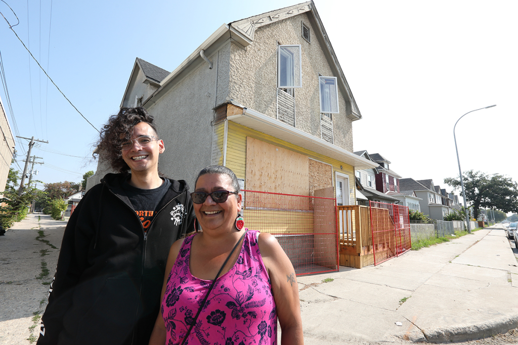 Zoongizi Ode team members pose outside one of three affordable housing units they are building.