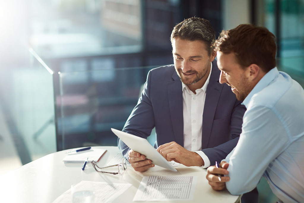 A businessman is meeting with his business lender in the office getting advice on how to establish his company's credit score.