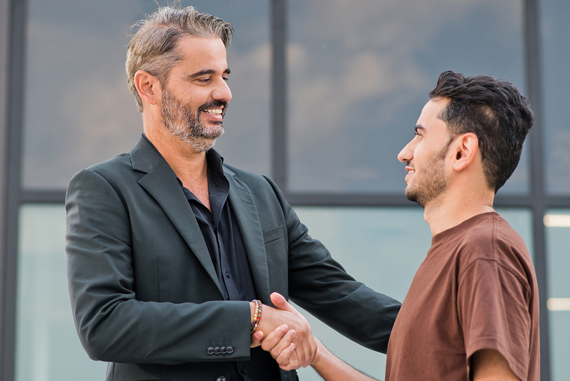 Fabricio Mendes, SVP Asset Management and Investor Relations, LS Properties, shakes hands with a man outside a building.