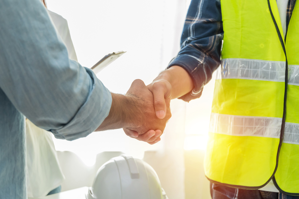 Builder and architect shake hands on construction site.